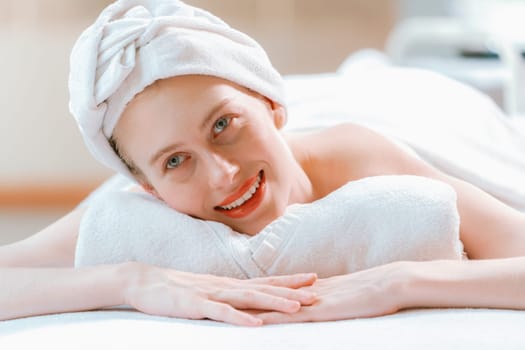 A beautiful young woman lies on a spa bed, her body relaxed and at peace. Pretty caucasian girl surrounded by the spa environment and the gentle aroma of essential oils. Close up. Tranquility.