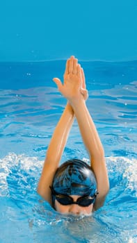 Preteen boy swimming in indoor pool having fun during swim class