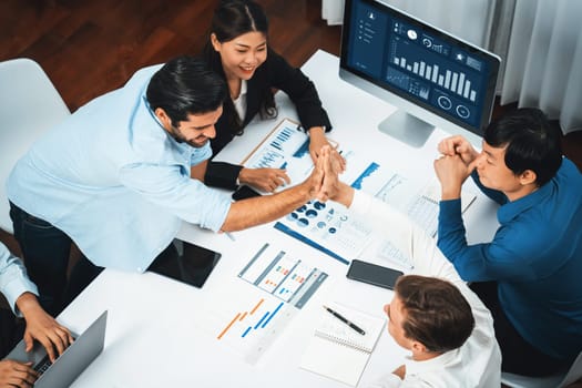 Diverse group of office employee worker high five after making agreement on strategic business marketing planning. Teamwork and positive attitude create productive and supportive workplace. Prudent