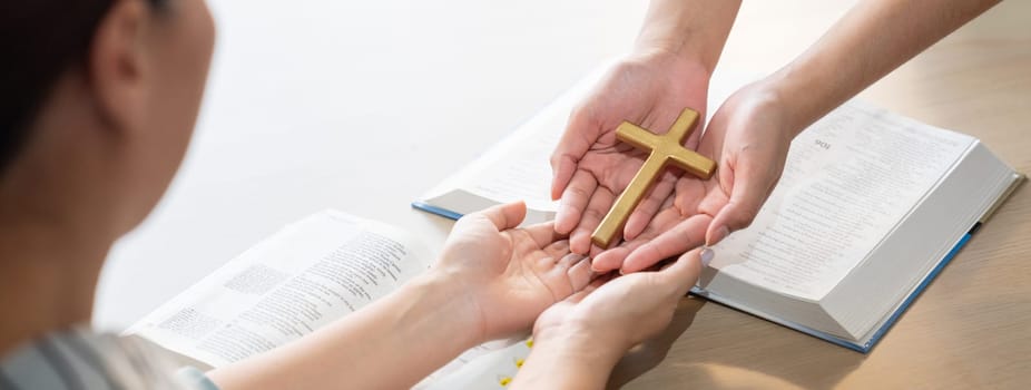 Close-up women prayer deliver holy bible book and holy cross to young believer. Spreading religion symbol. Concept of hope, religion, christianity and god blessing. Warm background. Burgeoning.