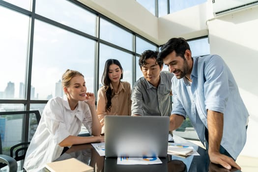 Asian project manager uses laptop displayed data analysis while professional business team brainstorming marketing idea at business meeting. Working together,sharing idea, planing strategy. Tracery.