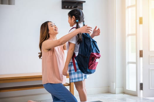 Loving mother and schoolgirl with backpack before first day, Asian mother hugging her daughter saying goodbye before go to school at home, parents and child little girl, back to school concept