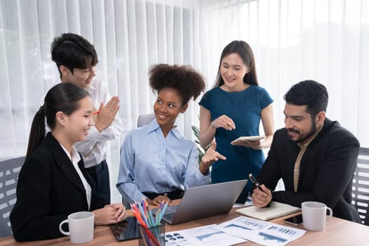 Multiracial analyst team use BI dashboard data to analyze financial report on meeting table. Group of diverse business people utilize data analysis by FIntech for success business marketing. Concord