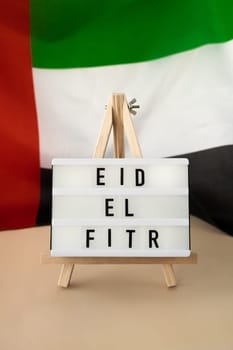 EID EL FITR - Eid Mubarak - Happy Holidays text frame on United Arab Emirates waving flag made from silk material. Public holiday celebration background. The National Flag of UAE. Patriotism Commemoration Day Muslim Ramadan Blessed Holy Month concept