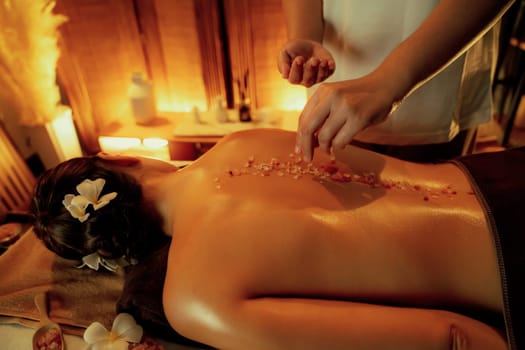 Woman customer having exfoliation treatment in luxury spa salon with warmth candle light ambient. Salt scrub beauty treatment in Health spa body scrub. Quiescent