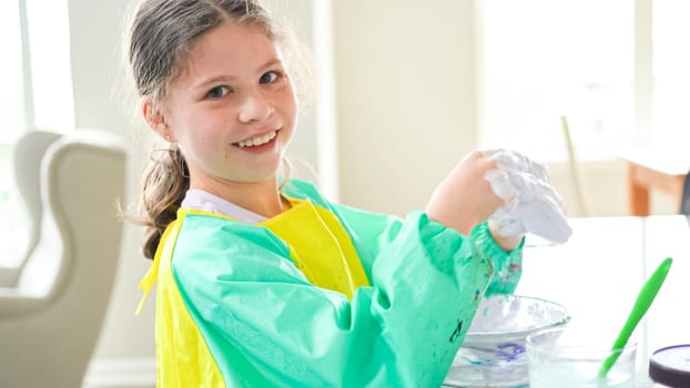 In a modern kitchen, a homeschooled girl is engrossed in creating homemade slime, a fun and educational hands-on project that enhances her creativity and problem-solving skills.