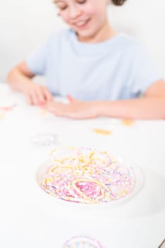 Little girl enjoys crafting colorful bracelets with vibrant clay beads set.