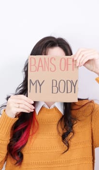 Young woman holding sign Bans Of My Body covering face. Anti domestic violence, racism racial discrimination. Stop abortion white background. Struggle for women rights, social problems