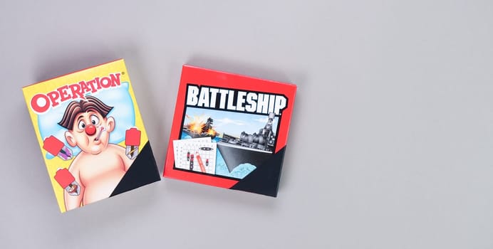 Mini board games on grey background. Fun games to play with kids. Boxes of Operation, Battleship games. Gatineau, QC Canada - 12-23-2022