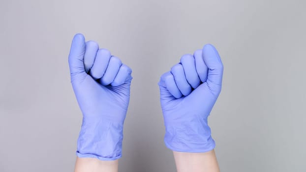 Hands in blue gloves of doctor or nurse over grey background with copy space. Medical gloves