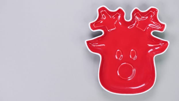 Festive table setting with red plate in Christmas raindeer shape on grey background. Holiday table decoration Top view. Space for text