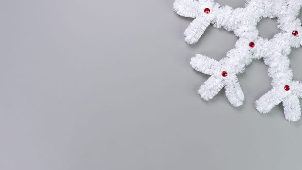 Fluffy white snowflake Christmas decor on a gray background. The concept of New Year and Christmas holidays, congratulations. Copy space. View from above.