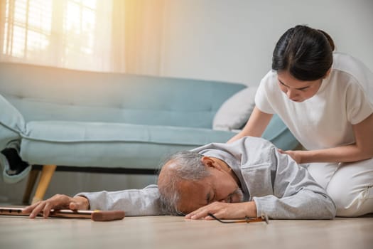 Asian elderly old man with walking stick fall on ground and granddaughter camp to help to support at home in living room, young woman halping her grandfather after falling down on floor, dizziness