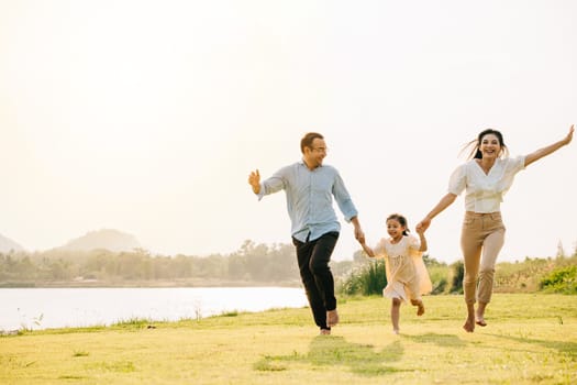 Happy family on vacation, running and laughing together in a green field, with the sun setting in the background and a feeling of togetherness and joy, Happy Family Day Concept