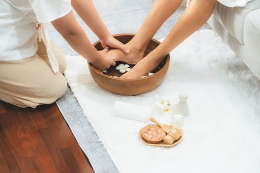 Woman indulges in blissful foot massage at luxurious spa salon while masseur give reflexology therapy in gentle day light ambiance resort or hotel foot spa. Quiescent