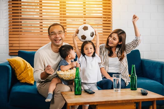 With popcorn in hand, a family and their daughter enjoy watching football on TV, fostering togetherness and excitement. Their cheers and smiles capture the joy of the game and shared happiness.