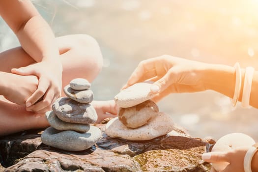 Balanced Pebbles Pyramid on the Beach on Sunny Day and Clear Sky at Sunset. Blue Sea on Background Selective focus, zen stones on sea beach, meditation, spa, harmony, calm, balance concept.