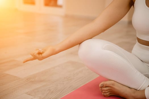 Girl does yoga. Young woman practices asanas on a beige one-ton background