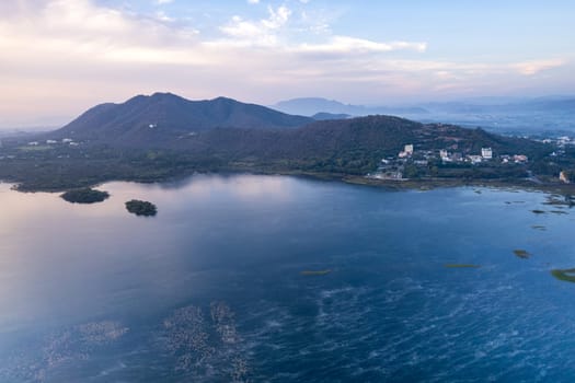 Aerial drone shot showing sunrise dawn dusk over aravalli hills lake pichola fateh sagar and cityscape in Udaipur, Chandigarh, Nainital showing famous tourist spot in India