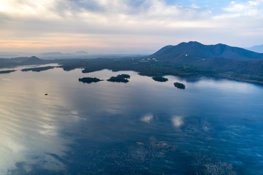 Aerial drone shot showing sunrise dawn dusk over aravalli hills lake pichola fateh sagar and cityscape in Udaipur, Chandigarh, Nainital showing famous tourist spot in India