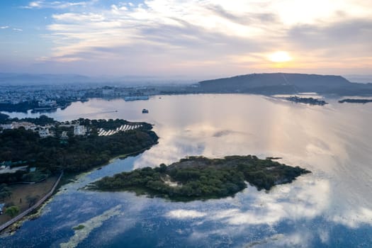 Aerial drone shot showing sunrise dawn dusk over aravalli hills lake pichola fateh sagar and cityscape in Udaipur, Chandigarh, Nainital showing famous tourist spot in India