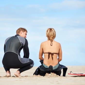 Surfing, talking and back of people on beach with surfboard for water sports, fitness and exercise by ocean. Nature, friends and man and woman for direction on holiday, vacation and adventure by sea.