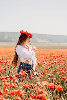 Happy woman in a poppy field in a white shirt and denim skirt with a wreath of poppies on her head posing and enjoying the poppy field