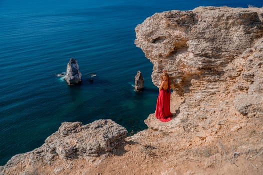 A woman in a red flying dress fluttering in the wind, against the backdrop of the sea