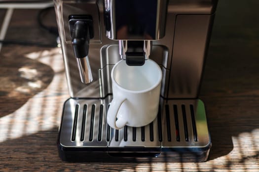 A sleek espresso machine fills a white mug with fresh coffee in a home setting.