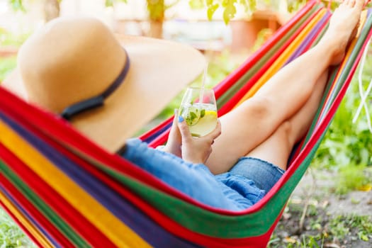 A person lounging in a colorful hammock, wearing a straw hat and holding a refreshing drink, enjoying a peaceful summer day.