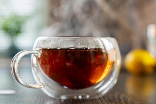 Close-up of a hot, steaming cup of tea on a wooden table with a blurred background.