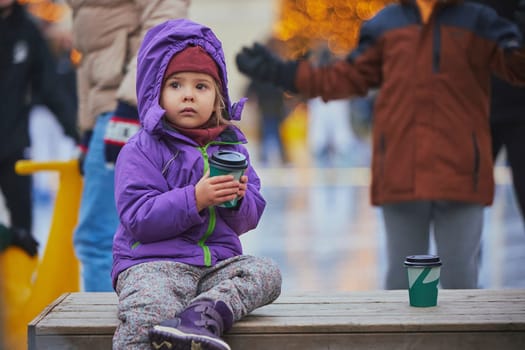 Charming child drinking coffee on the skating rink in Denmark.