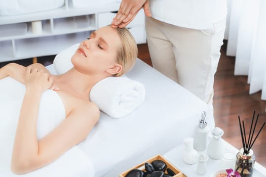 Caucasian woman enjoying relaxing anti-stress head massage and pampering facial beauty skin recreation leisure in dayspa modern light ambient at luxury resort or hotel spa salon. Quiescent