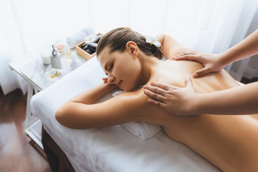 Caucasian woman customer enjoying relaxing anti-stress spa massage and pampering with beauty skin recreation leisure in day light ambient salon spa at luxury resort or hotel. Quiescent