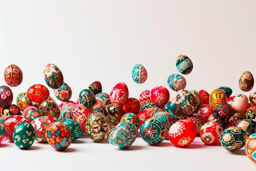 A large number of Easter eggs on a white background. The Easter eggs are painted with different coloured paints. Some of the eggs lie on a white tabletop. A few eggs fall from above.