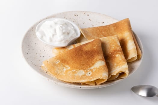 Stack of russian thin pancakes blini with fresh sour cream.