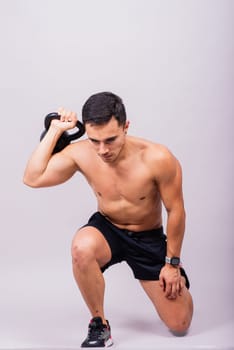 Sporty man working out with kettlebell. Photo of man on dark background. Strength and motivation