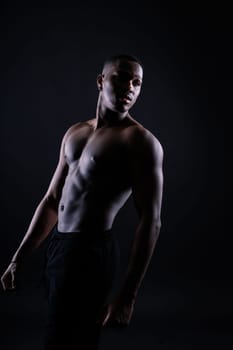 One young african muscular build man standing topless silhouette isolated on a black background