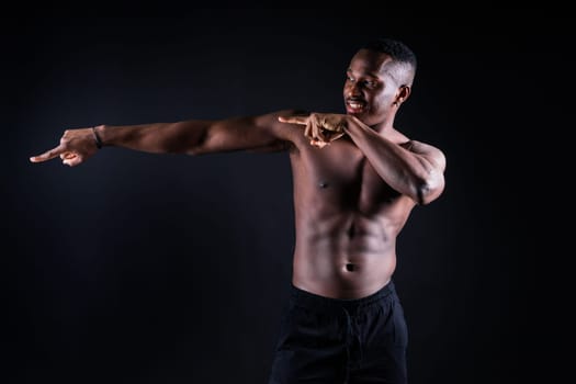 One young african muscular build man standing topless silhouette isolated on a black background