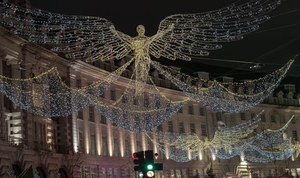 London, UK - Dec 25, 2023 - Flying angel Christmas decoration led lights display. Dramatic view of the traditional Christmas decoration lights hanging above Regent Street during dusk, The Spirit of Christmas, Light Festival in London, Space for text, Selective focus.