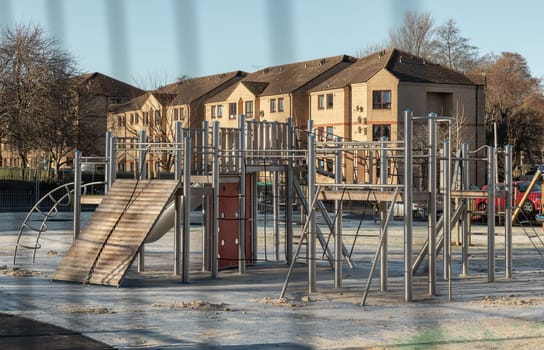 Edinburgh, Scotland, Jan 17, 2024 - The Children's playground with Slide. Empty outdoor playground with stainless steel equipment for children, Looking through iron fence, Copy space, Selective focus.