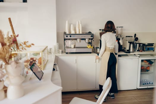 Professional female barista grind coffee bean with grinder machine while working in cafe