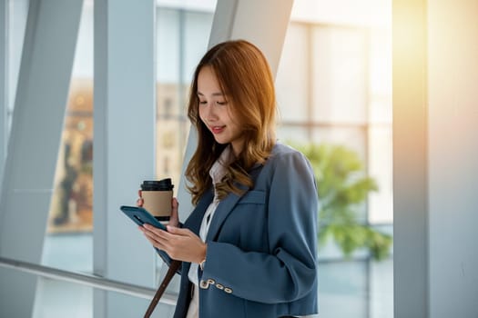 Professional woman on escalator holding coffee and smartphone. Ideal for business and technology-related themes. Modern city background. Business lifestyle on the go concept