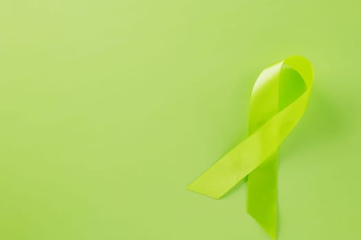 Green awareness ribbon symbol of Gallbladder and Bile Duct Cancer month isolated on green background with copy space, concept of medical and health care support, Cancer awareness, World bipolar day