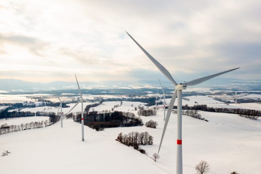 Windmill park or wind turbines in the winter field at sunset. Production of clean energy