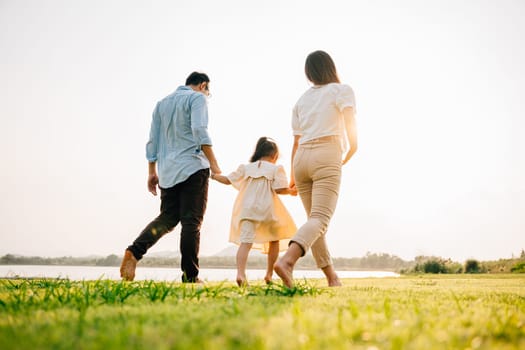 A man and a woman running together in a green field on a summer day, holding hands and feeling the joy of being in love, happy family day, Back view