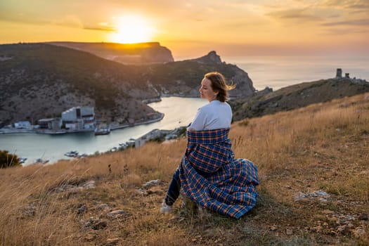 Happy woman on sunset in mountains. Woman siting with her back on the sunset in nature in summer. Silhouette