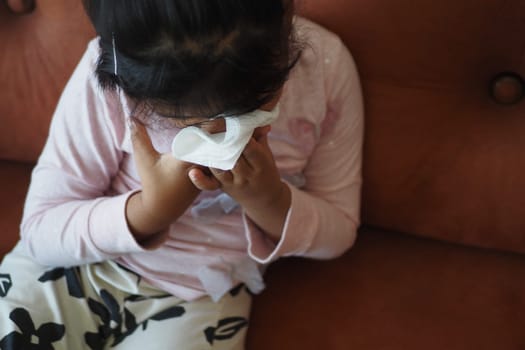 Sick child with flu blow nose with napkin