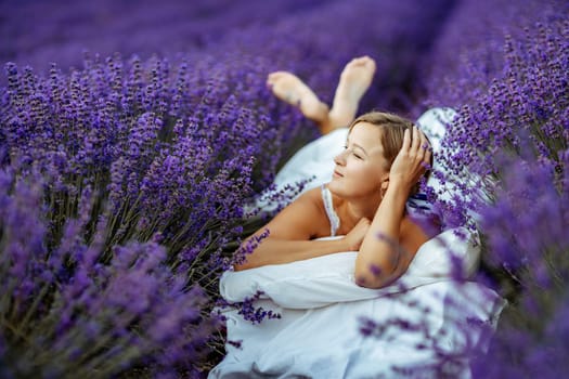 A middle-aged woman lies in a lavender field and enjoys aromatherapy. Aromatherapy concept, lavender oil, photo session in lavender.