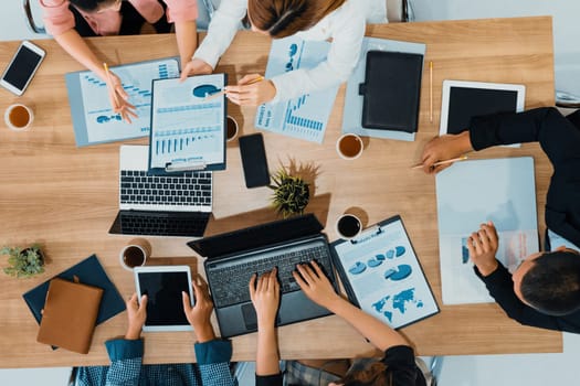 Top view of businessman executive in group meeting with other businessmen and businesswomen in modern office with laptop computer, coffee and document on table. People corporate business team uds